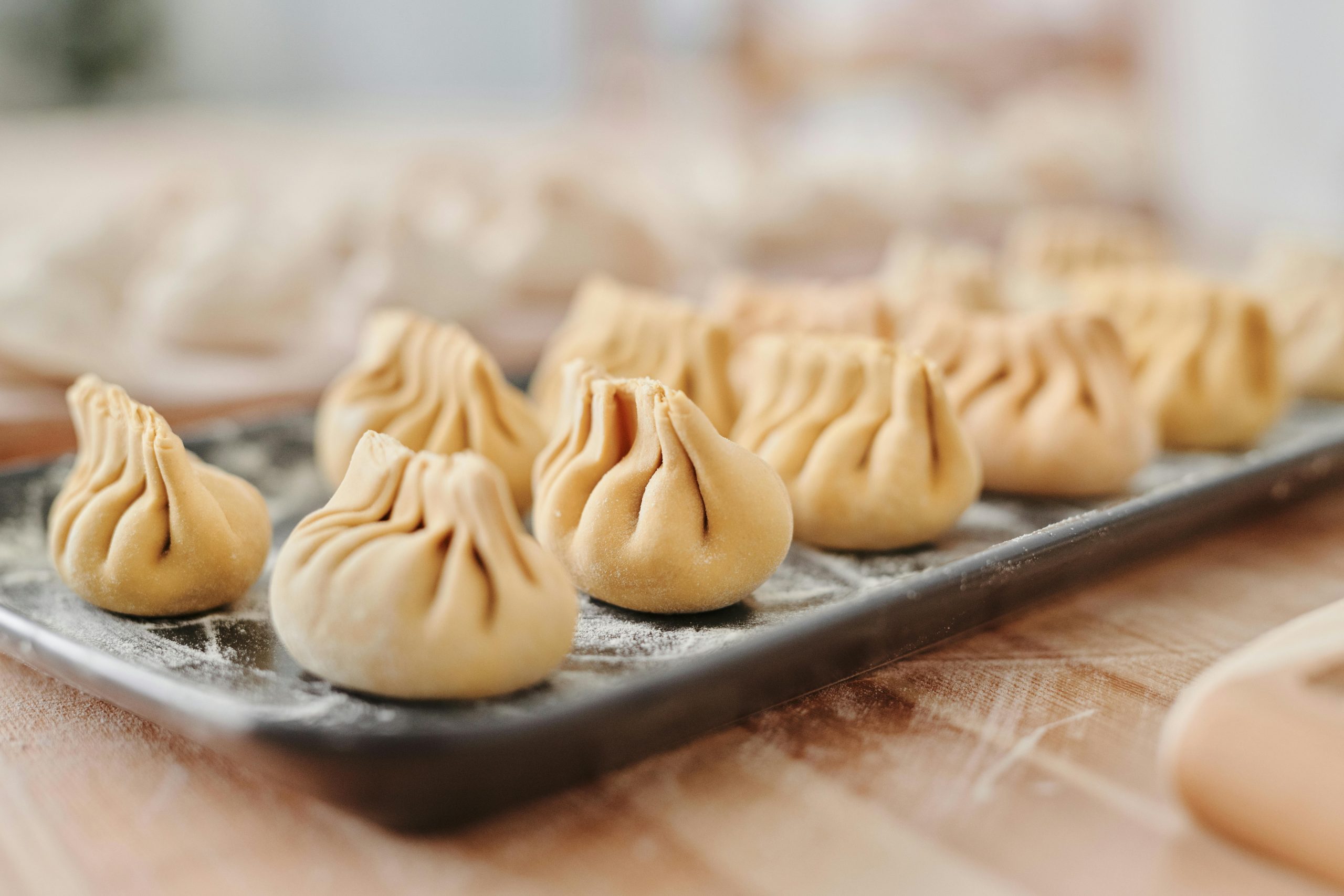 Close-up view of uncooked traditional dumplings on a floured tray, ready for cooking.